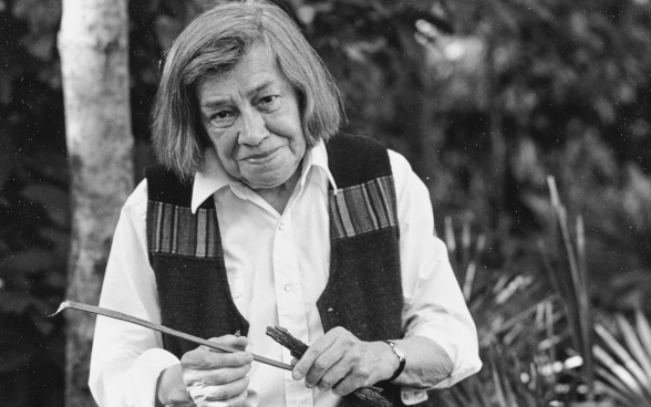 Fotografie: Patricia Highsmith sitzt in ihrem Wohnort Tegna an einem Granittisch und liest eine Zeitung